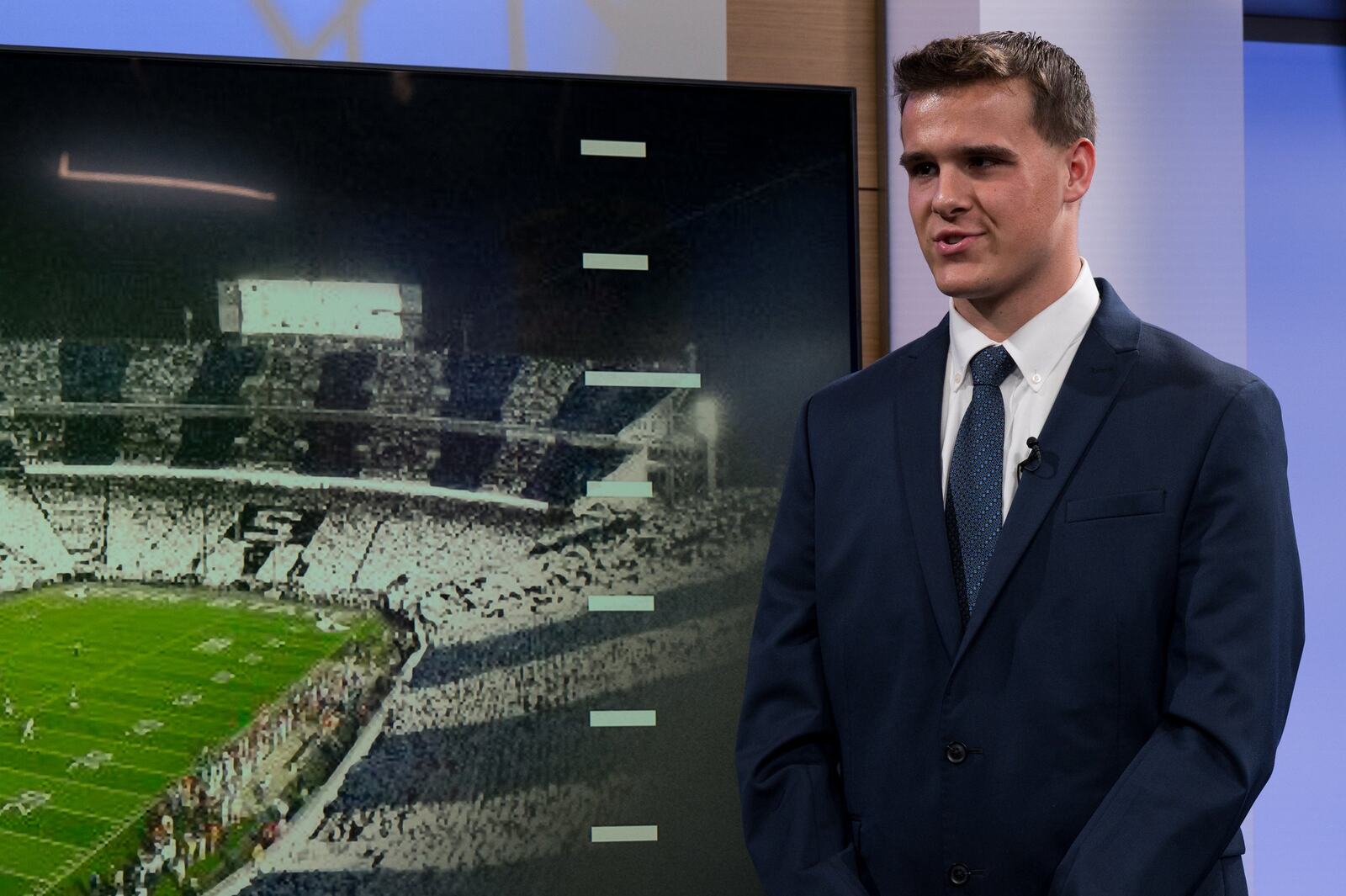 Joseph Draper reports from the studio set with Beaver Stadium on screen at Penn State in State College, Pennsylvania