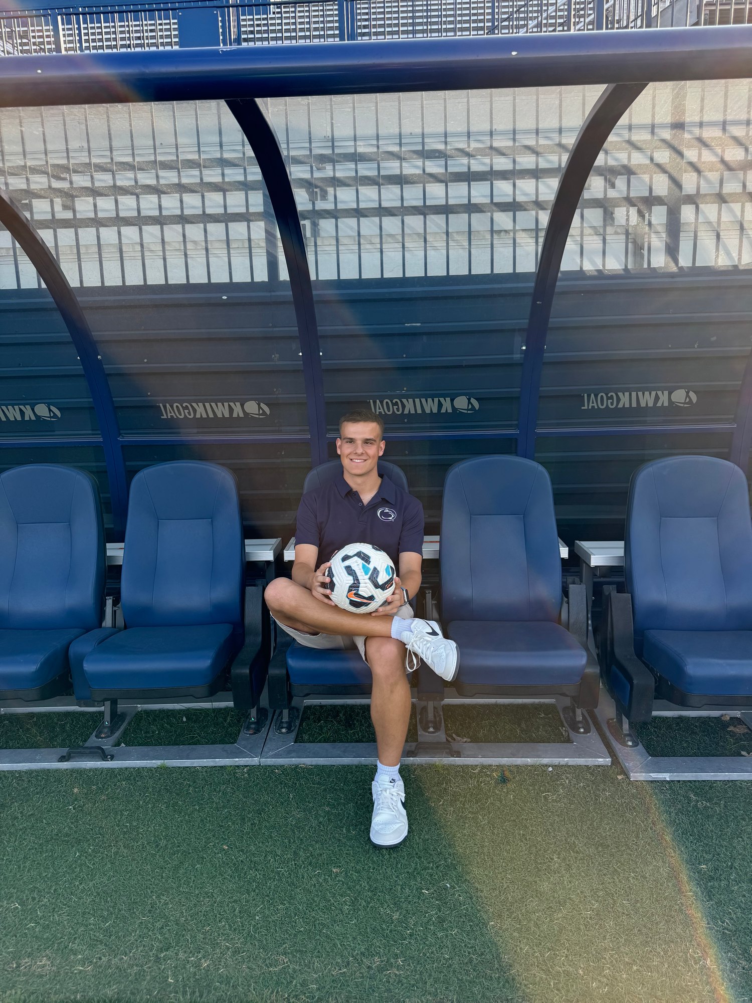 Joseph Draper holds a soccer ball on the team benches at a Penn State soccer venue in State College, Pennsylvania